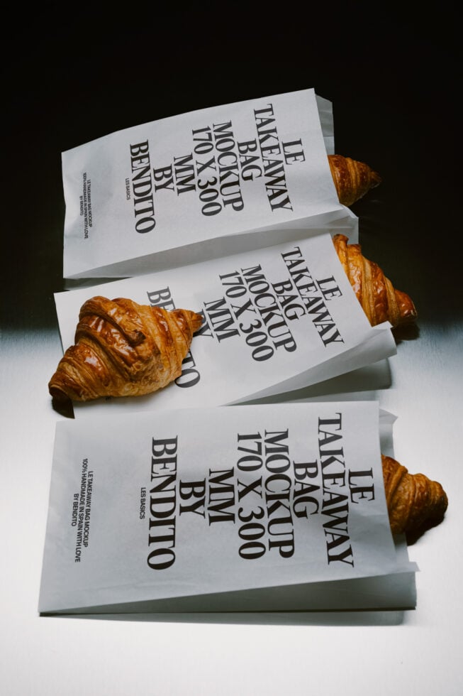 Stacked takeaway bags with croissants, mockup showing text layout on white paper packaging