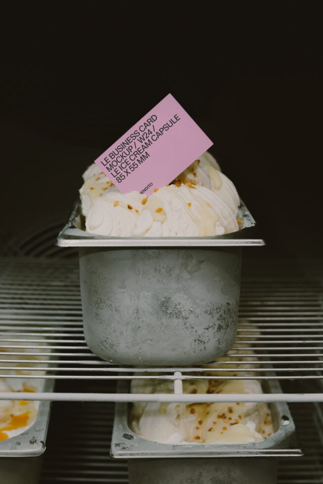 Pink business card mockup tilted on creamy dessert in concrete cup, dark background
