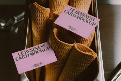 Pink business cards draped over textured waffle cones in a metal tray, overhead shot