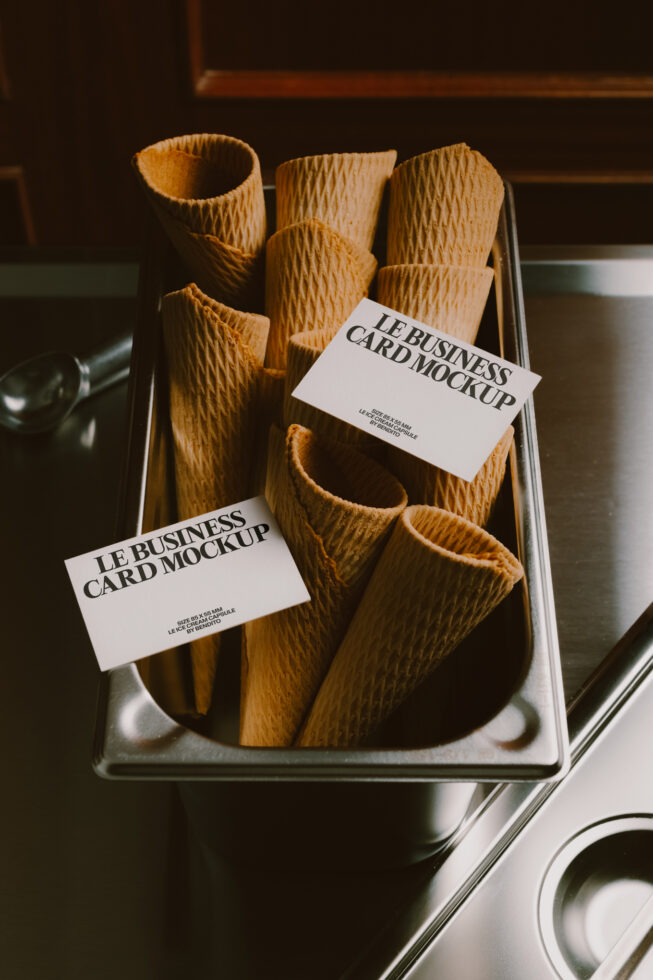 Business cards propped on woven paper cones in a metal tray, moody lighting
