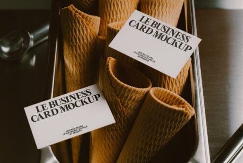 Business cards draped over textured wooden vases in a styled flat lay setup