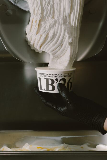 Ice cream pouring from mixer into labeled tub mockup with dark background