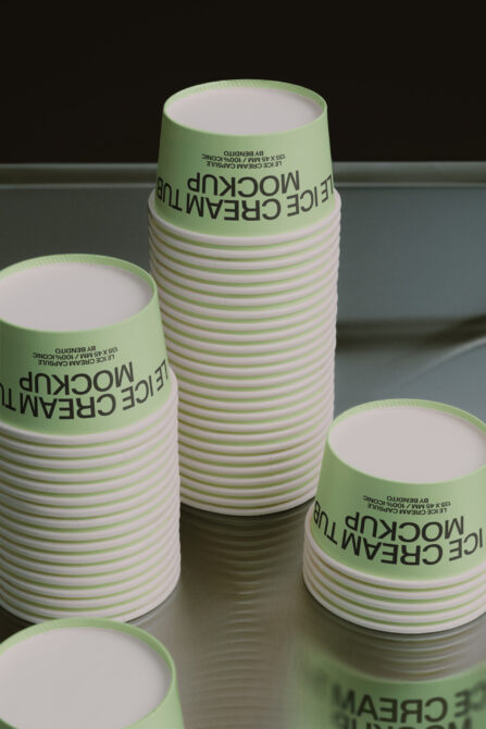 Stacked green striped paper cups with black text label on gray surface