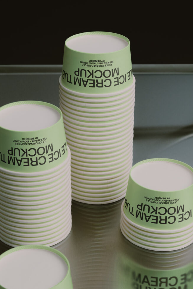 Stacked green striped paper cups with black text label on gray surface