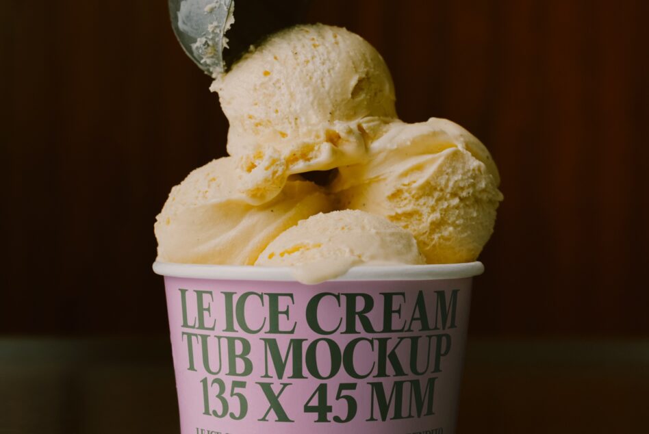 Vanilla ice cream scoops in pink tub with green text label on dark background