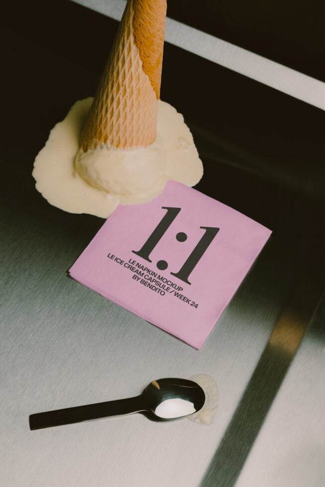 Napkin mockup with pink card showing 1.1 logo, paintbrush applying cream, black spoon nearby