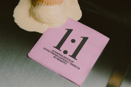 Folded pink napkin mockup with large serif numbers, cream container beside it on textured surface