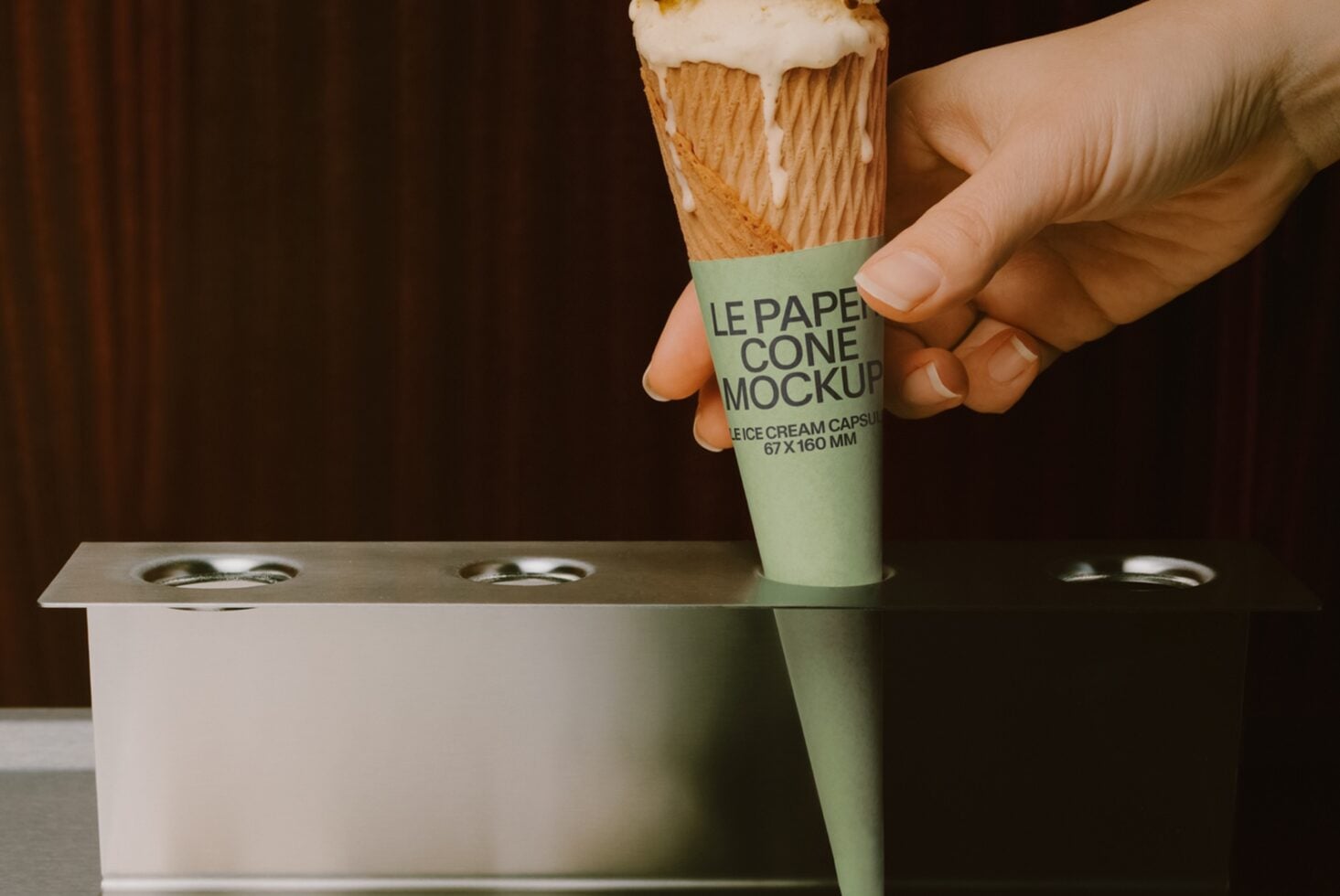 Hand holding ice cream cone with sage green paper wrapper mockup over container