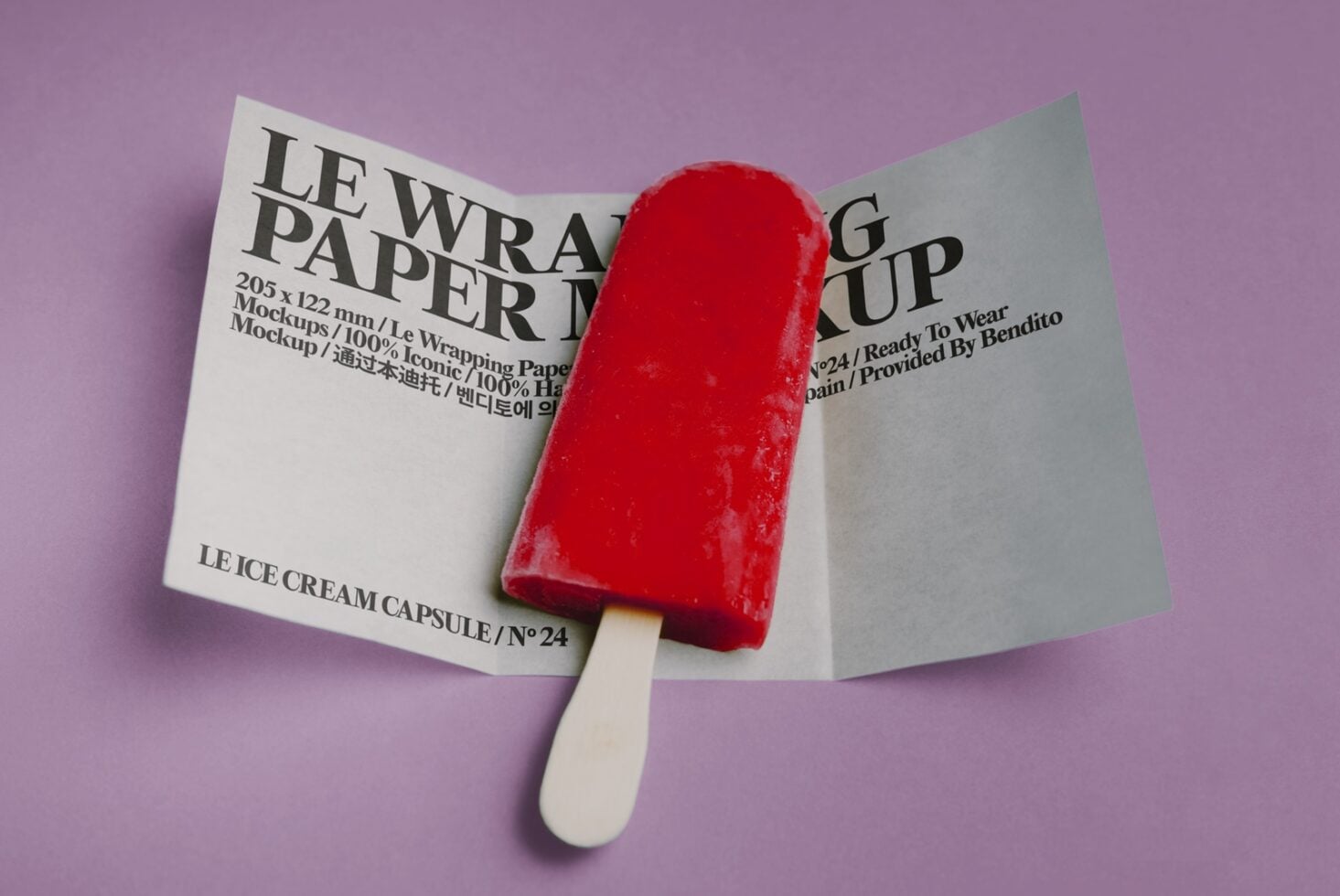 Bright red popsicle with cream stick positioned on open folded wrapping paper mockup against lavender background