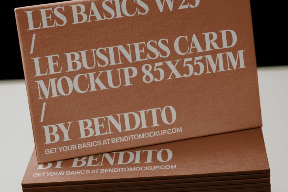 Stacked business cards in warm tan cardstock with modern sans serif typography, angled view showing depth
