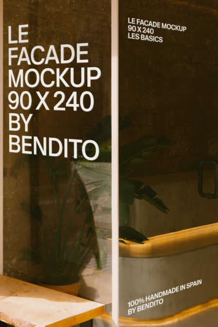 Storefront window mockup with warm lighting, potted plant, wooden bench, textured bronze wall, gold trim details