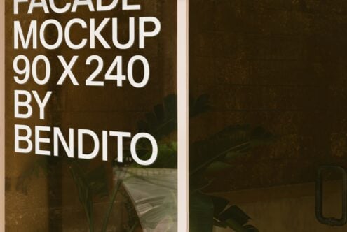 Building facade mockup 90x240 with white sans serif text on weathered brick, plants visible through glass