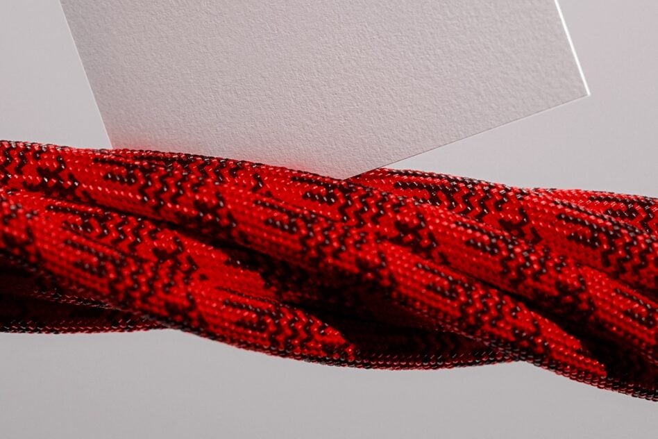 Blank business card mockup with red patterned fabric draped across neutral background