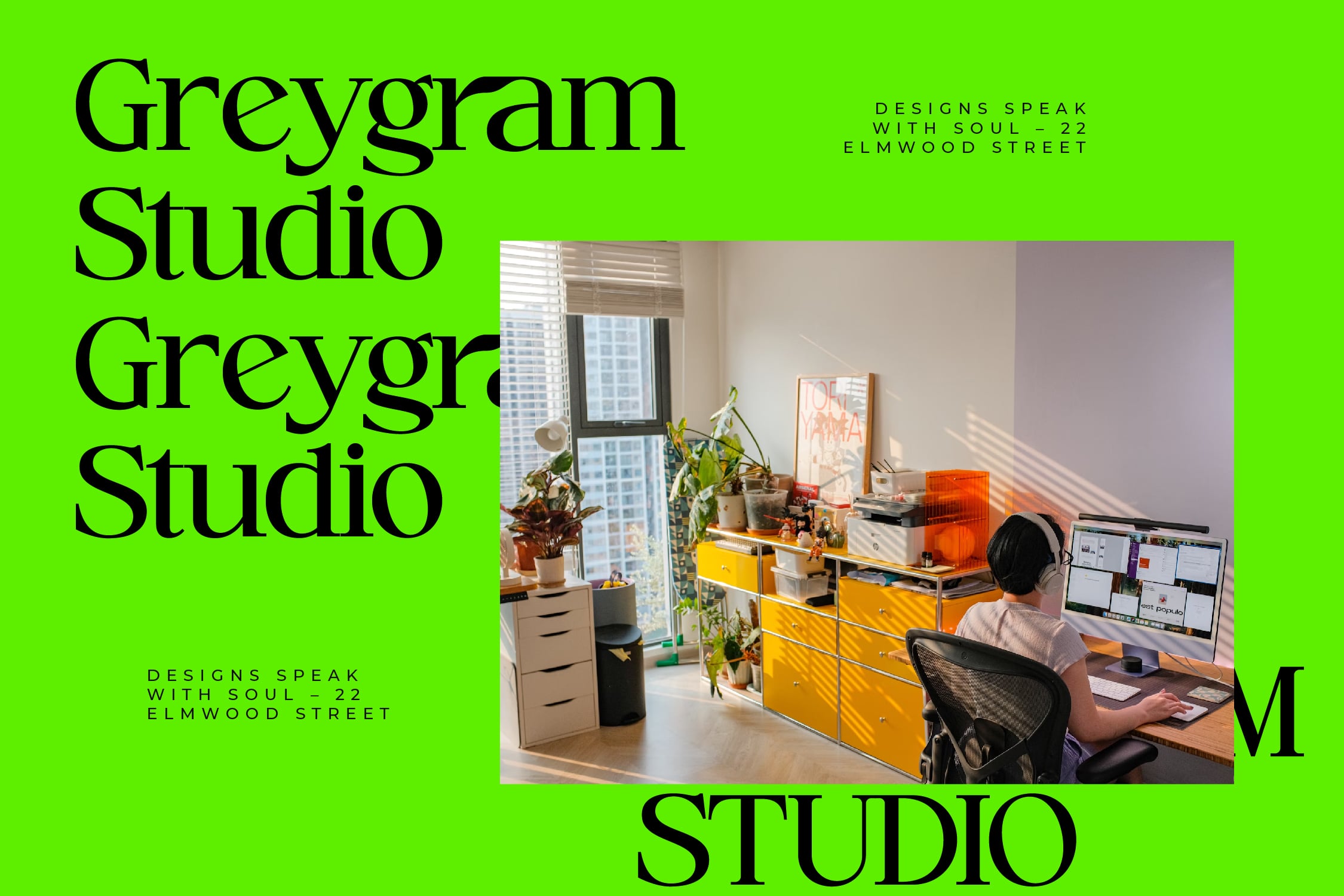 Designer working at bright yellow desk with plants, dual monitors, high-rise window view