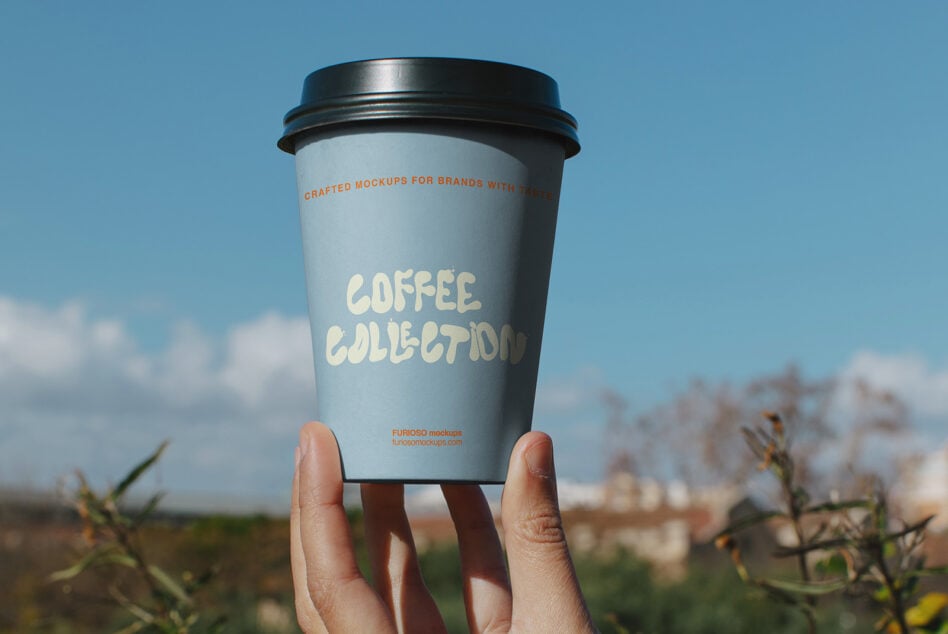 Coffee cup mockup held up to bright sky with cream colored branding text