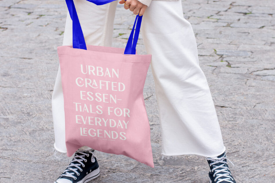 Pink tote bag mockup with blue handles, street style shot showing text placement on fabric