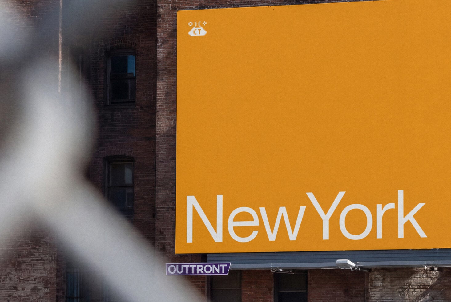 Bright yellow billboard with "New York" text on weathered brick building facade