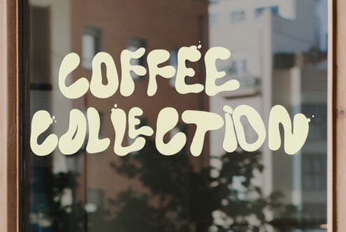 Coffee collection window decal with cream wavy lettering on glass storefront
