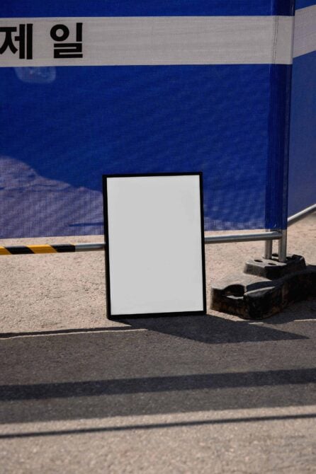 Blank poster mockup leaning against bright blue shipping container with Korean text