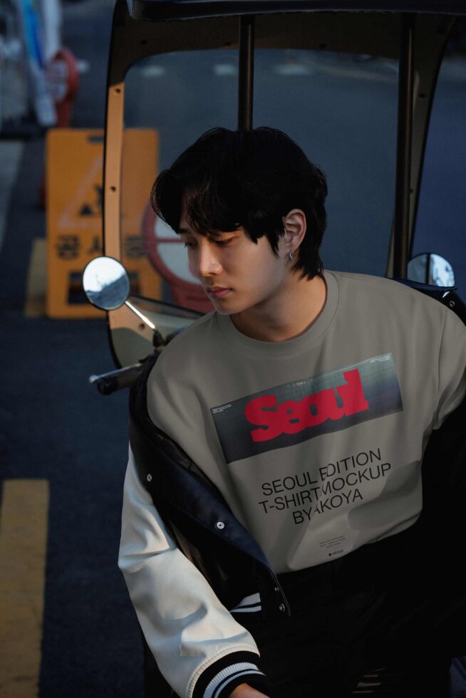 Guy on scooter wearing beige tee with bold red graphic text, urban street vibes