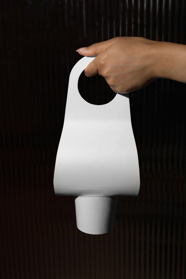 Hand holding blank white door hanger against dark textured background
