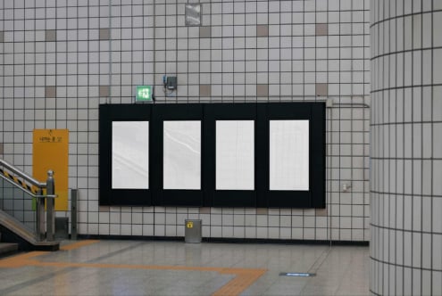 Four-panel black storefront mockup on tiled subway wall with exit sign above