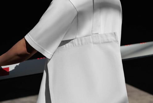 Close-up of white sport shorts on model with black background, showing seam details