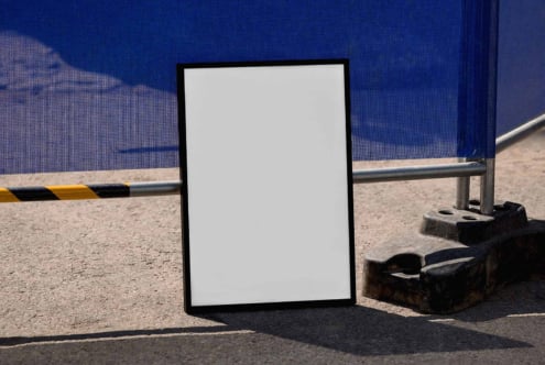 Blank poster mockup leaning against industrial construction site with blue wall backdrop