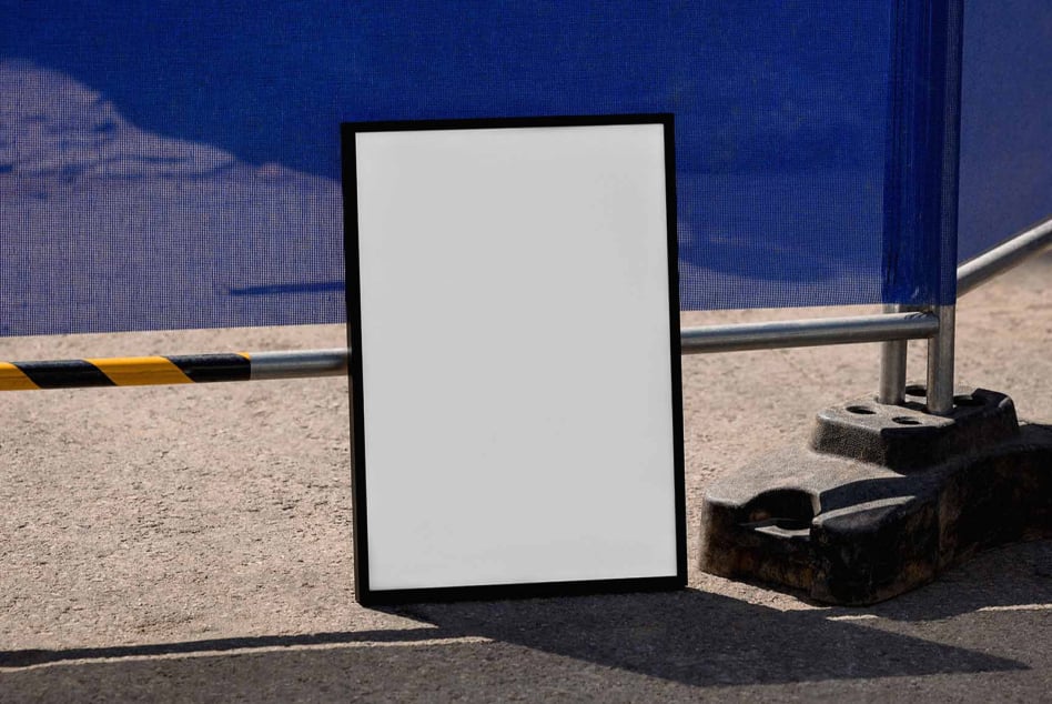 Blank poster mockup leaning against industrial construction site with blue wall backdrop