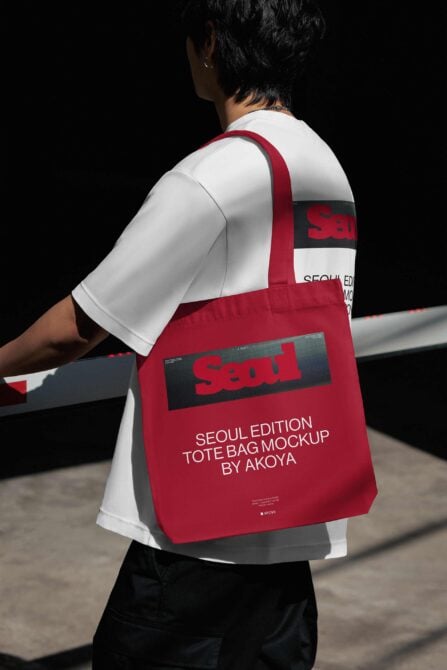 Person wearing white tee carrying red tote bag with Seoul branding, shot from back angle