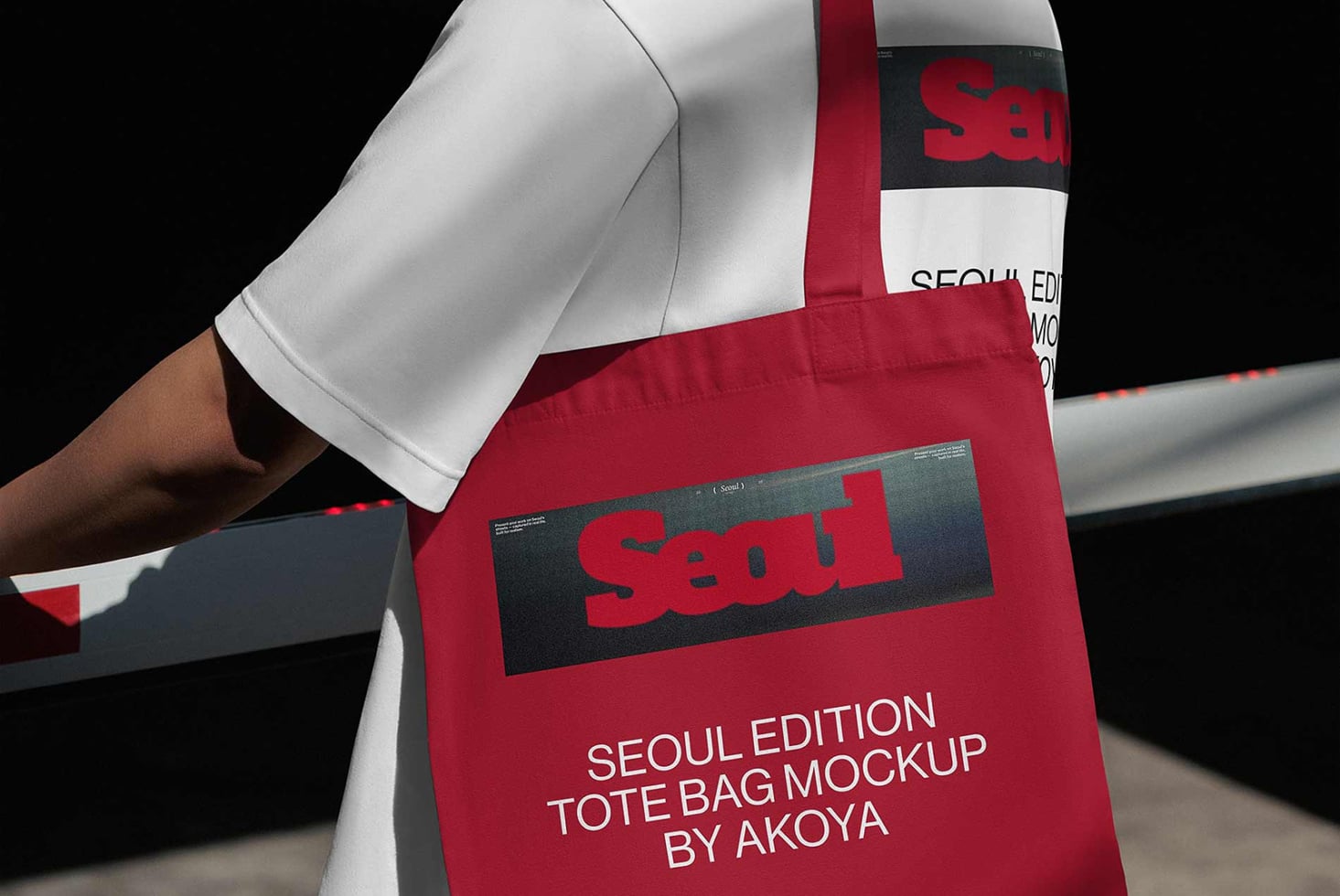 Red tote bag mockup with bold branding on dark label, worn over white sleeve