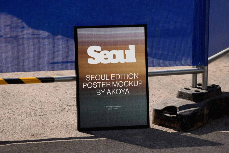 Framed poster leaning against blue wall on gritty Seoul street with metal railing
