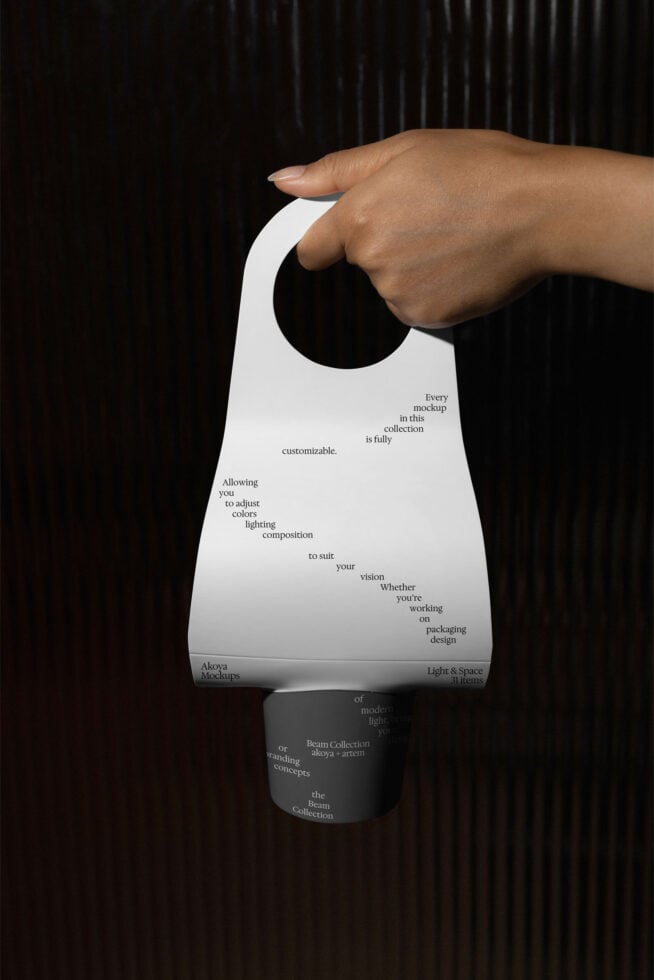 Hand holding white door hanger mockup with customizable text on dark striped background