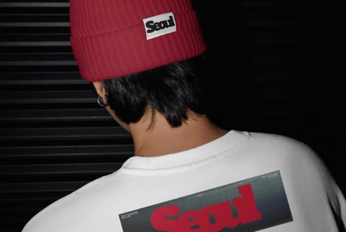 Person wearing red ribbed beanie with Seal label, white sweatshirt with red Seal graphic on back