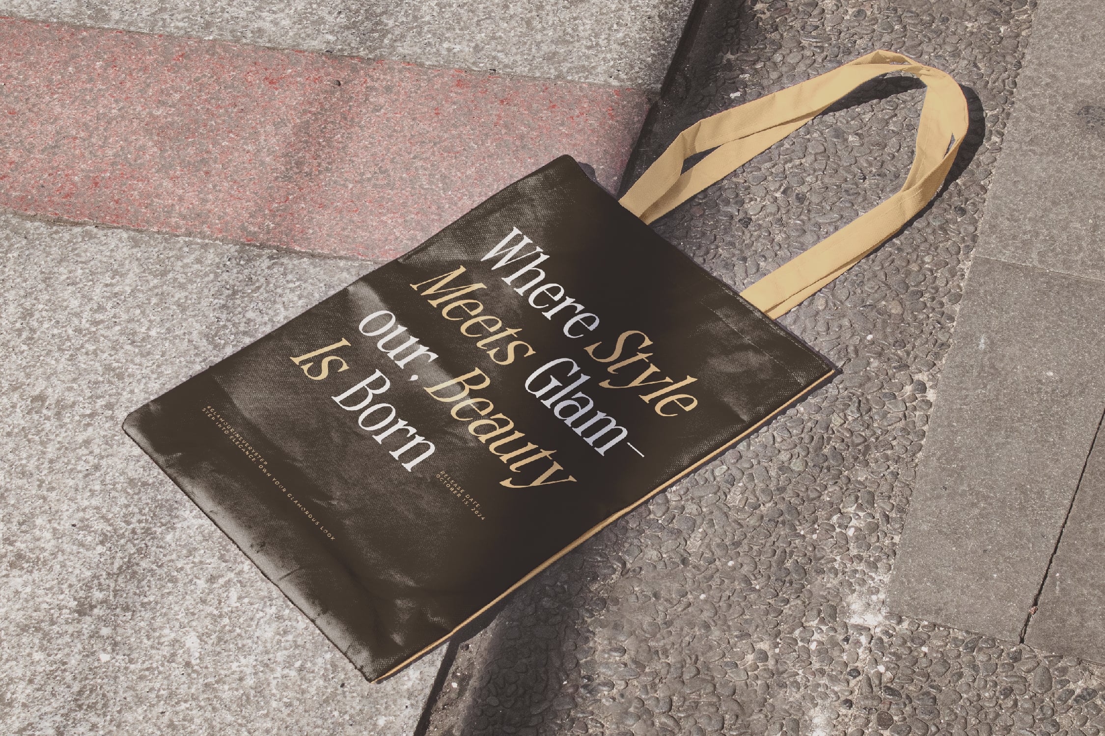 Black canvas tote bag with gold lettering on concrete ground mockup