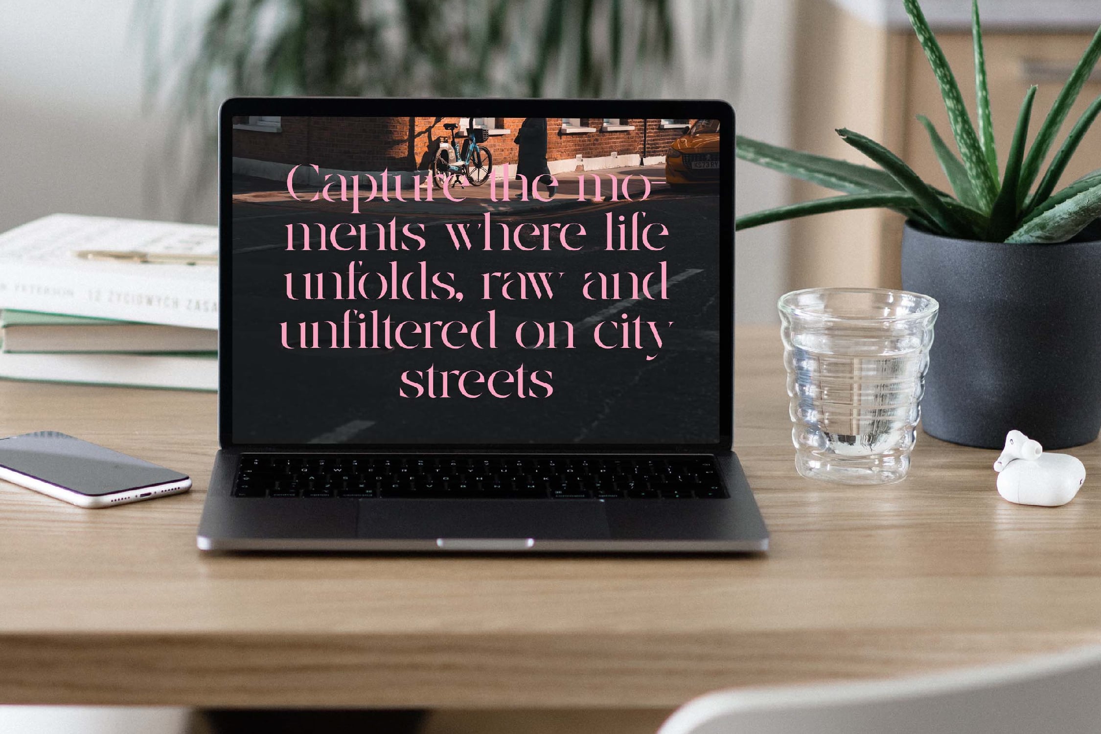 Laptop mockup on wooden desk with rose gold text overlay, plants, books, water glass, phone nearby