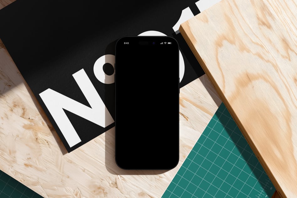 Black phone on wood desk with design materials, geometric shapes, cool minimal setup shot