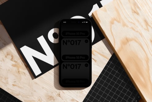 iPhone 16 Pro mockup surrounded by design materials on wood desk with geometric layouts