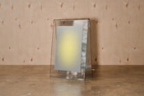 Glass tent card mockup with cream paper insert on textured wood surface