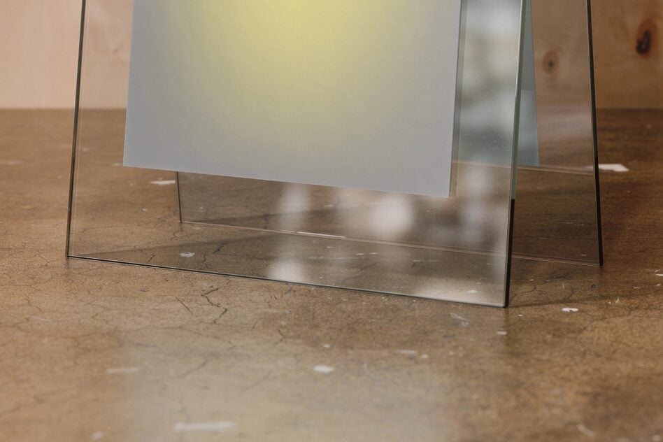 Blank acrylic desk sign with metal feet on concrete surface with shadows