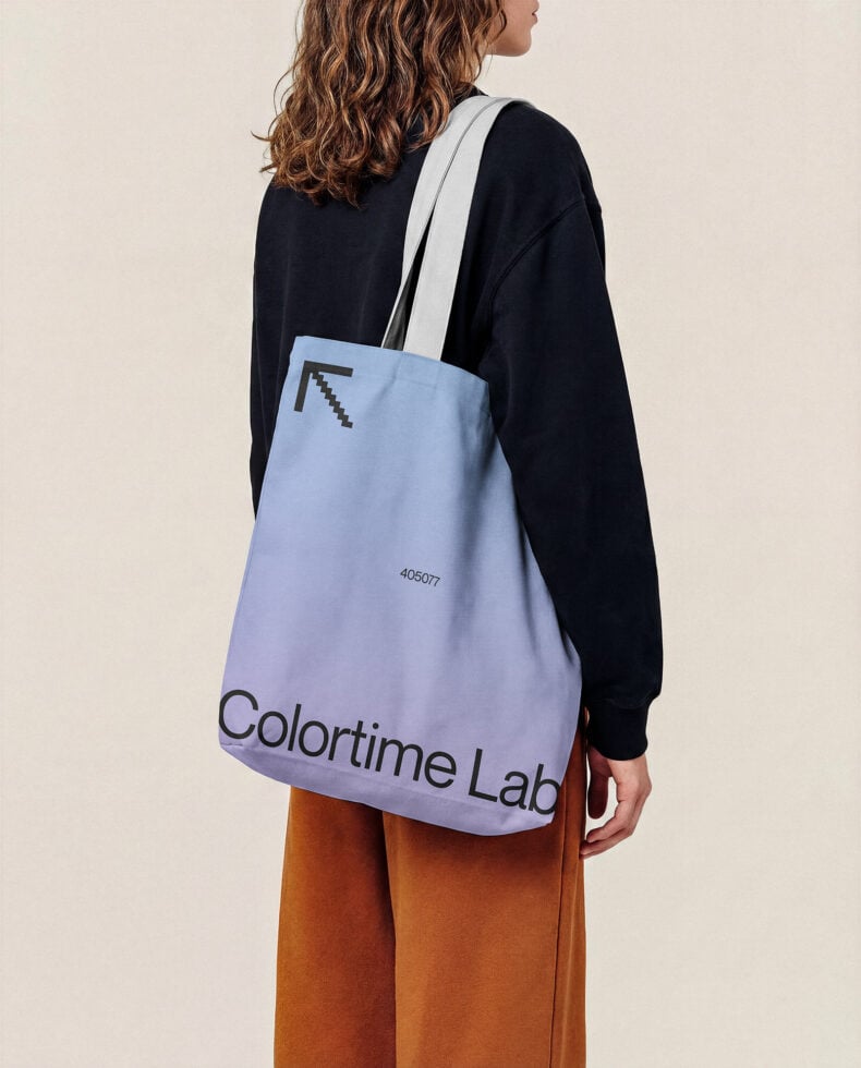 Woman wearing light blue tote bag with pixel arrow logo, Colortime Lab branding, white strap