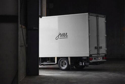 Delivery truck side view with cursive logo on white cargo box in industrial garage