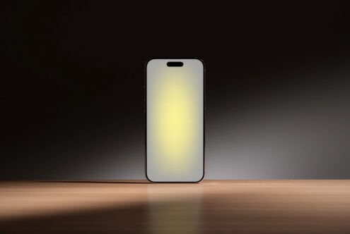iPhone 14 Pro mockup with blank screen on wooden surface, dark studio backdrop