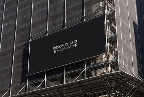 Large black billboard on construction scaffolding displaying Mockup Lab branding with Japanese text