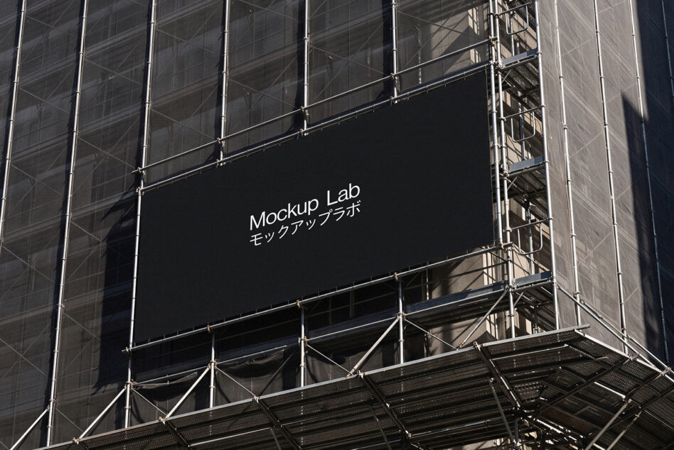 Large black billboard on construction scaffolding displaying Mockup Lab branding with Japanese text