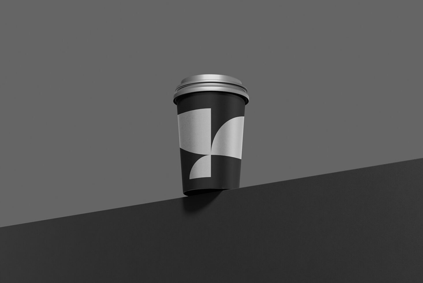 Black coffee cup mockup with geometric quarters design on gray surface