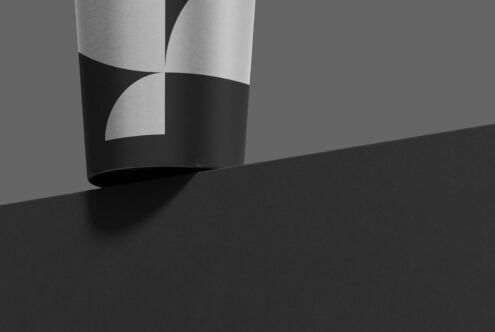 Rolled paper with geometric cutouts casting shadows on dark surface