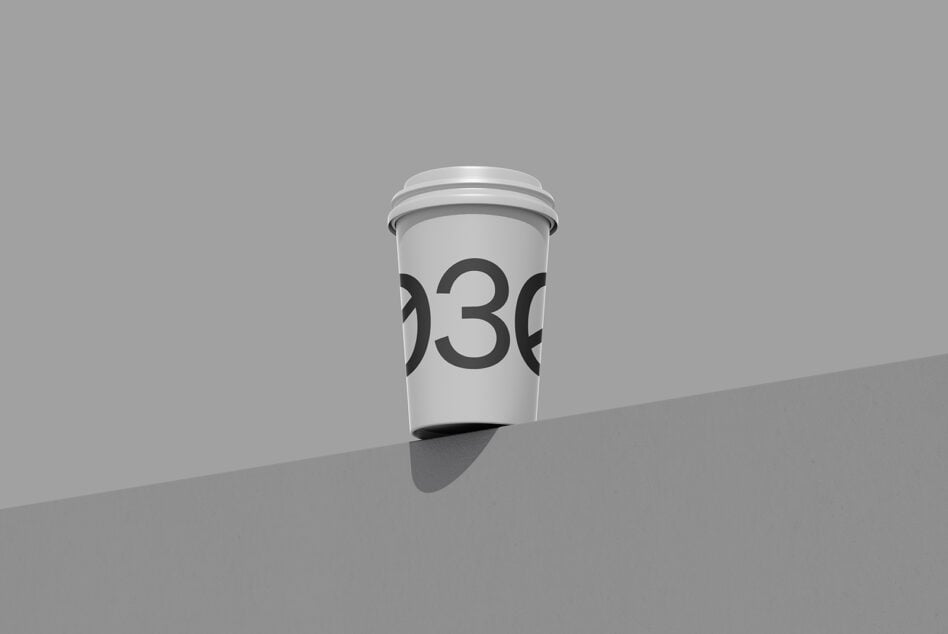 Minimalist coffee cup mockup with large numbers on white cup, casting shadow on gray surface