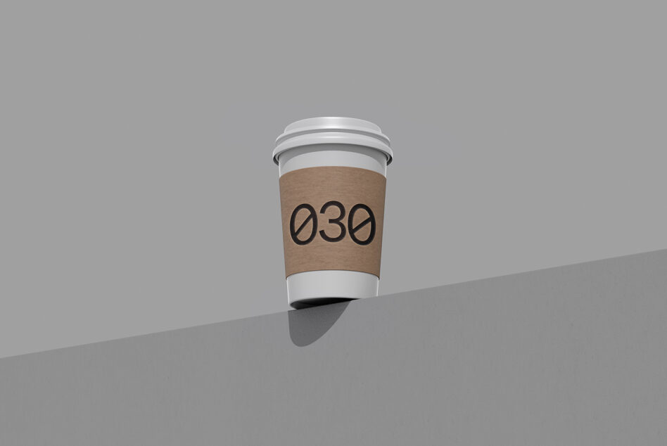 Coffee cup mockup with brown kraft sleeve showing 030 number on gray surface