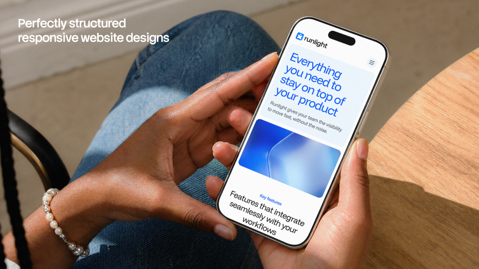 Hand holding iPhone showing blue gradient website design with product copy